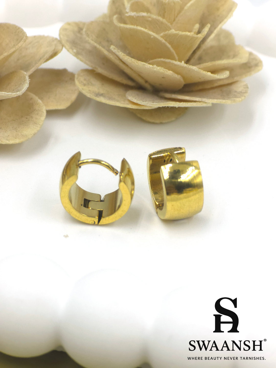 Swaansh Urban Edge matte gold huggie hoop earrings placed on white ceramic plate with floral decor in background
