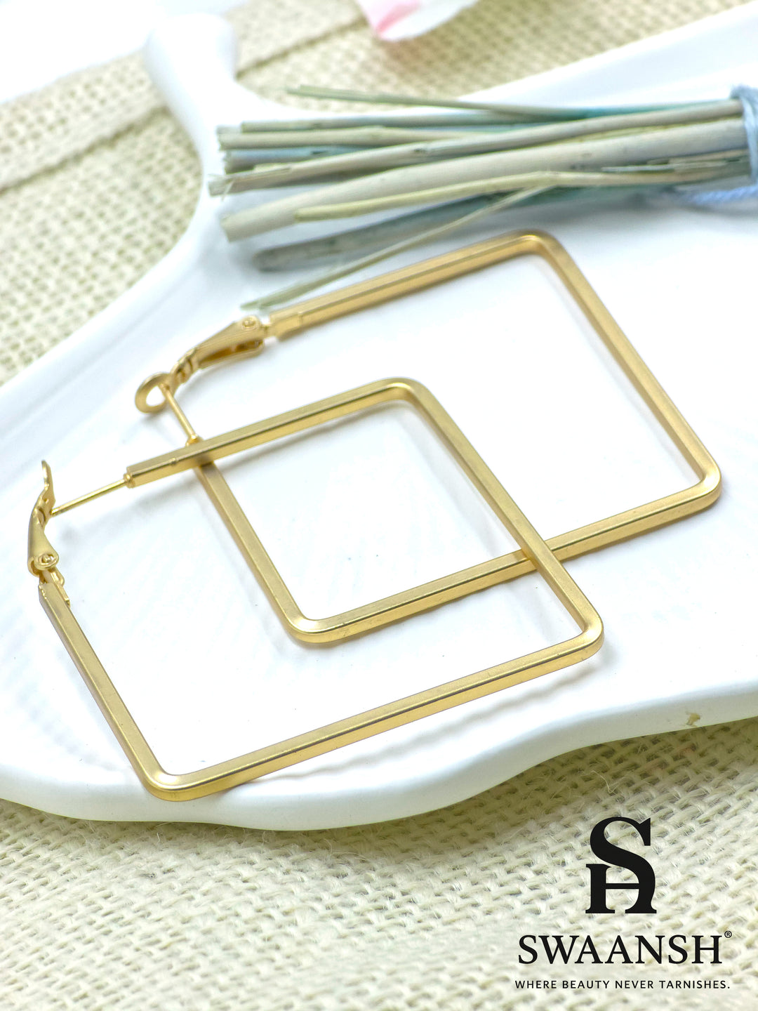Frame It Bold square gold hoop earrings by Swaansh placed on white ceramic plate – edgy geometric design for everyday and party wear