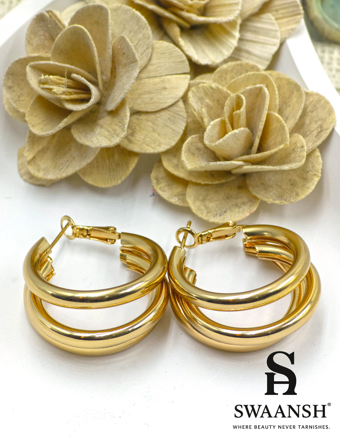 Bold Loop triple-band hoop earrings in gold by Swaansh, featuring thick layered design placed on a floral white base – ideal for statement wear