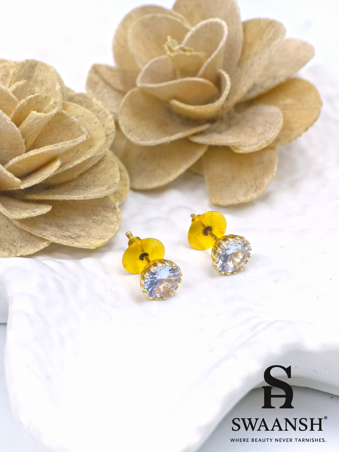Crystal solitaire gold stud earrings placed on white ceramic plate – Swaansh