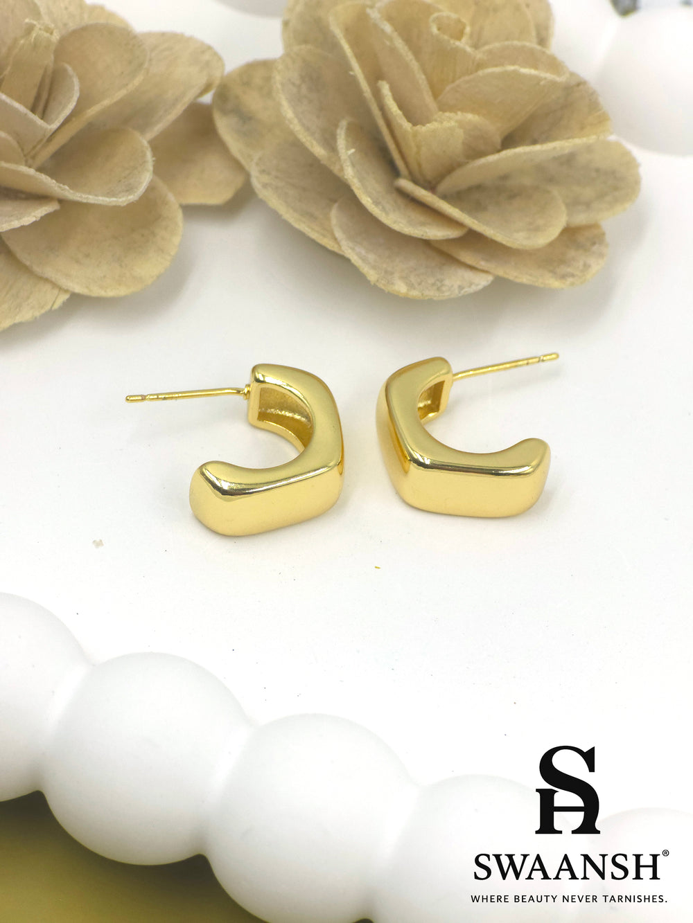 Swaansh Bold Drape earrings – smooth sculpted C-shaped gold mini hoops resting on white floral background