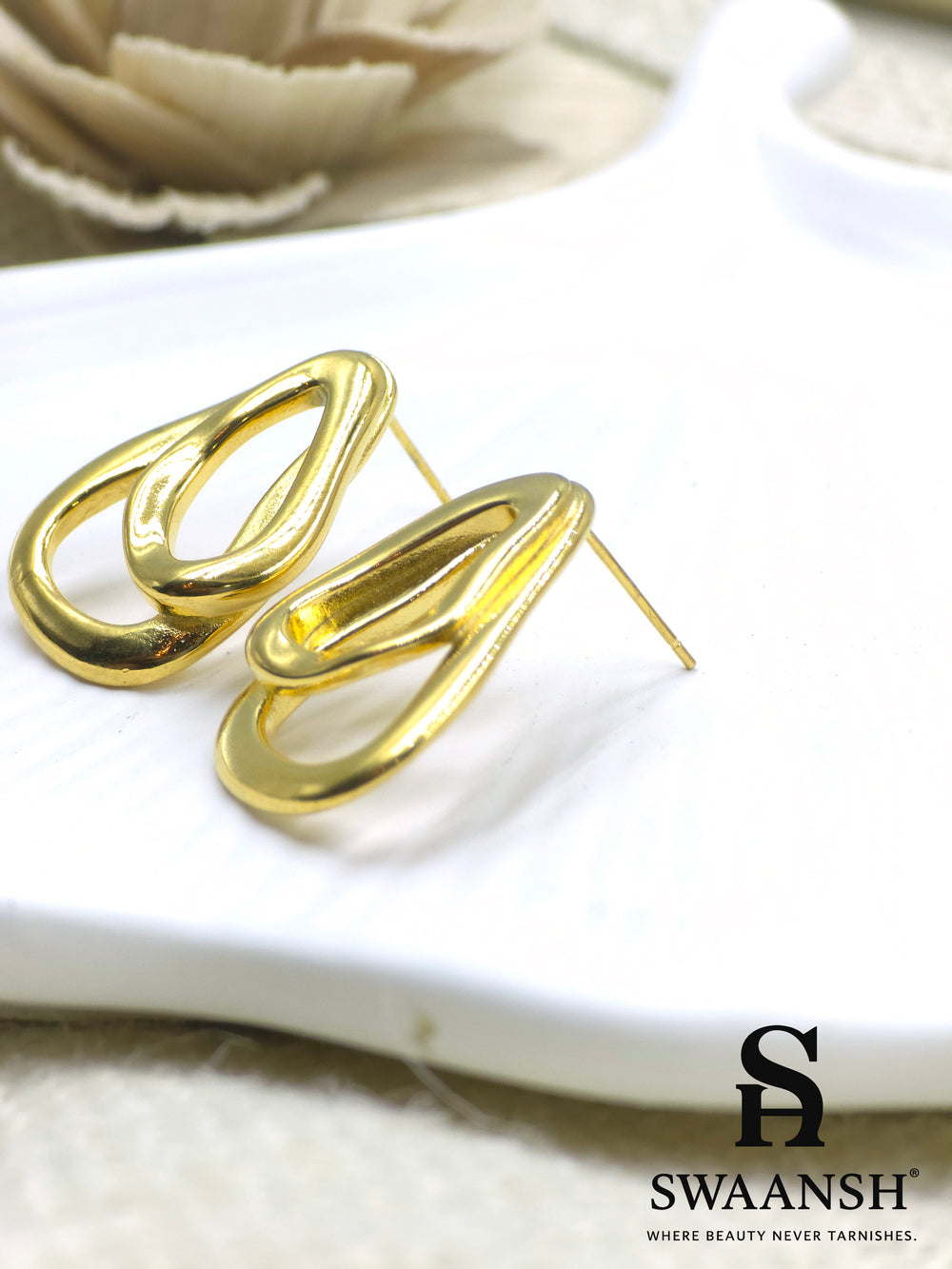 RippleLinks sculpted drop link earrings with glossy gold finish by Swaansh, styled on a white ceramic backdrop