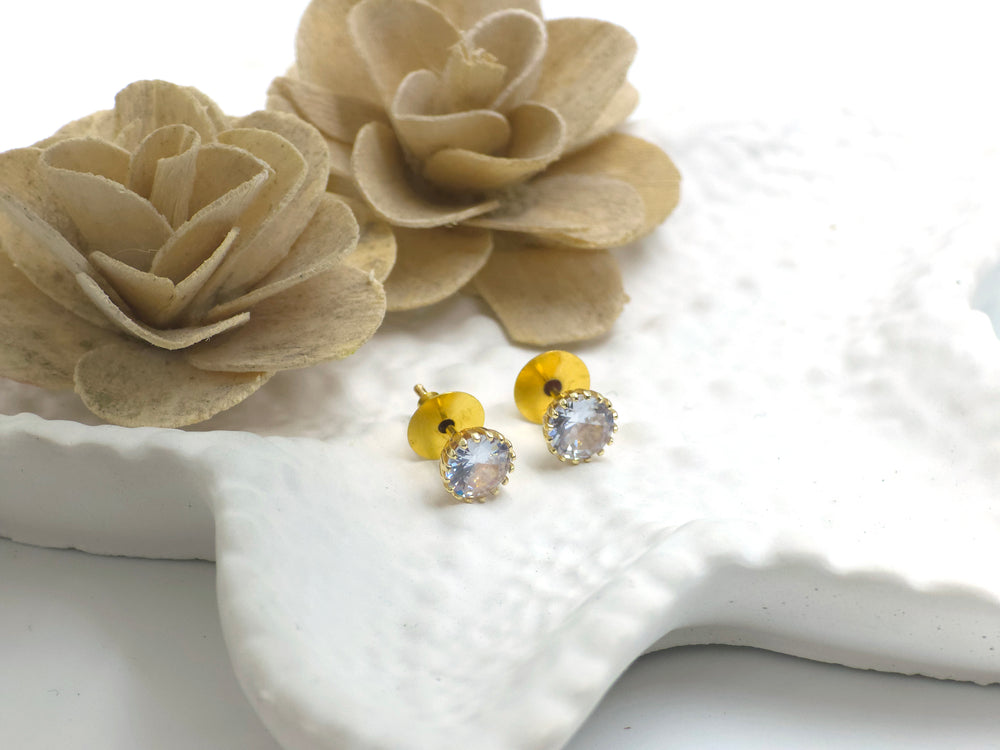 Crystal solitaire gold stud earrings placed on white ceramic plate – Swaansh