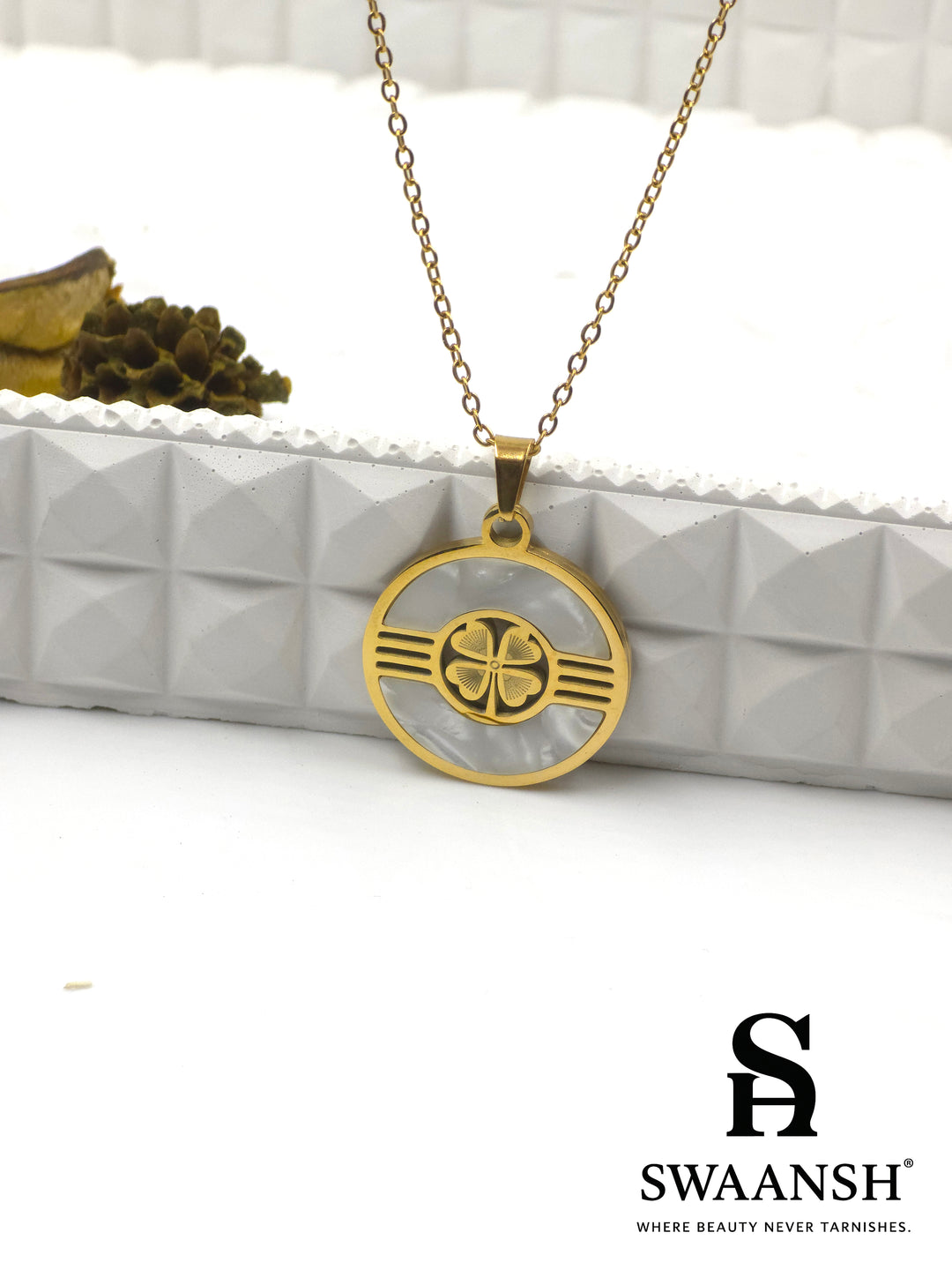 Gold-toned circular pendant with four-petal motif on mother-of-pearl base — Aura Shield Pendant by Swaansh