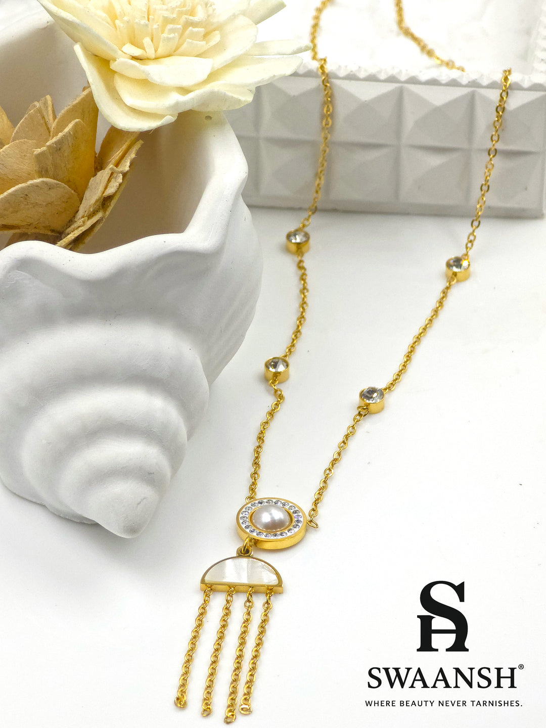 Lunar Drift Pendant by Swaansh featuring pearl center with crystal halo, half-moon charm, and gold tassel drops on crystal-dotted chain