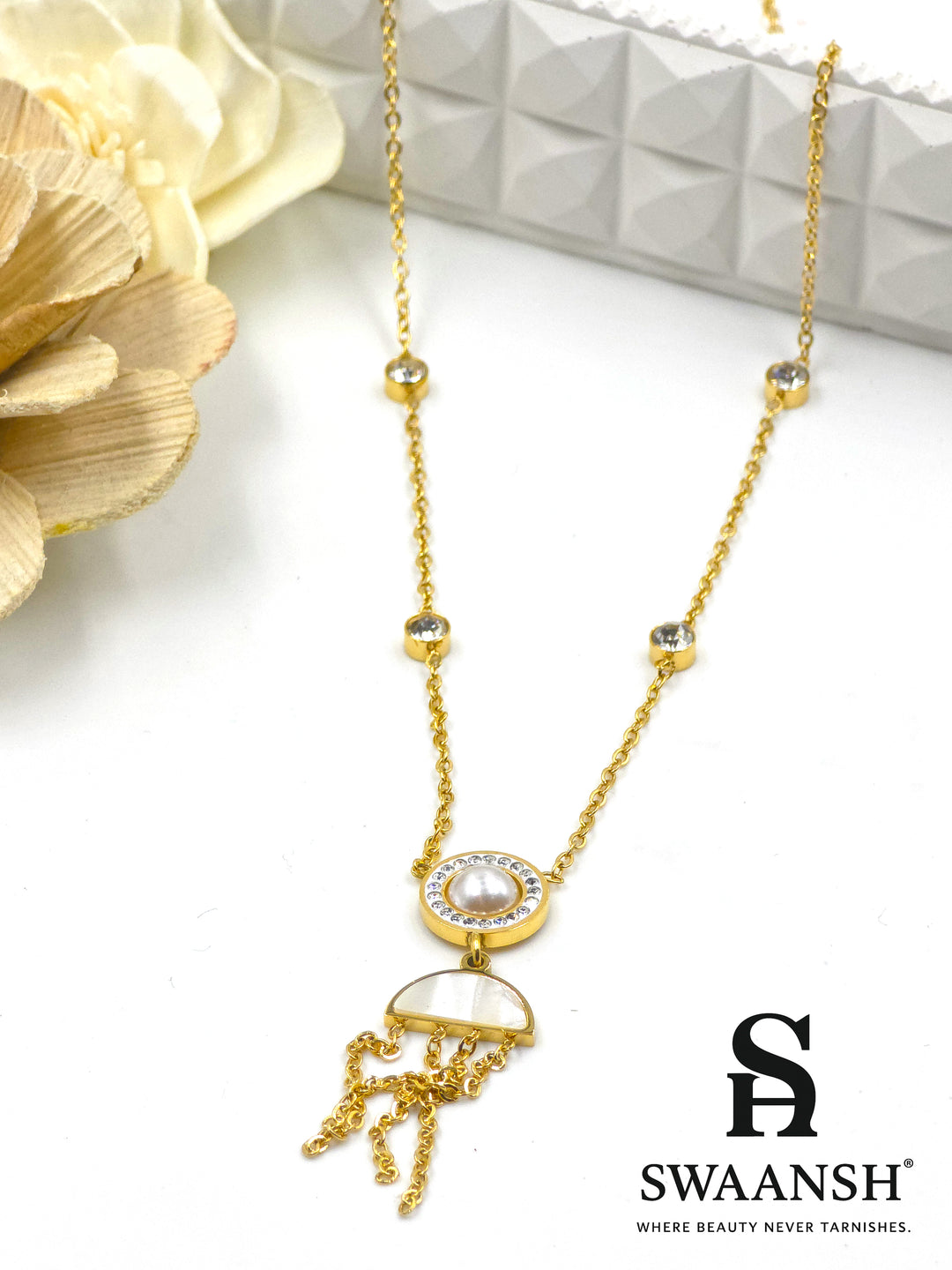 Lunar Drift Pendant by Swaansh featuring pearl center with crystal halo, half-moon charm, and gold tassel drops on crystal-dotted chain